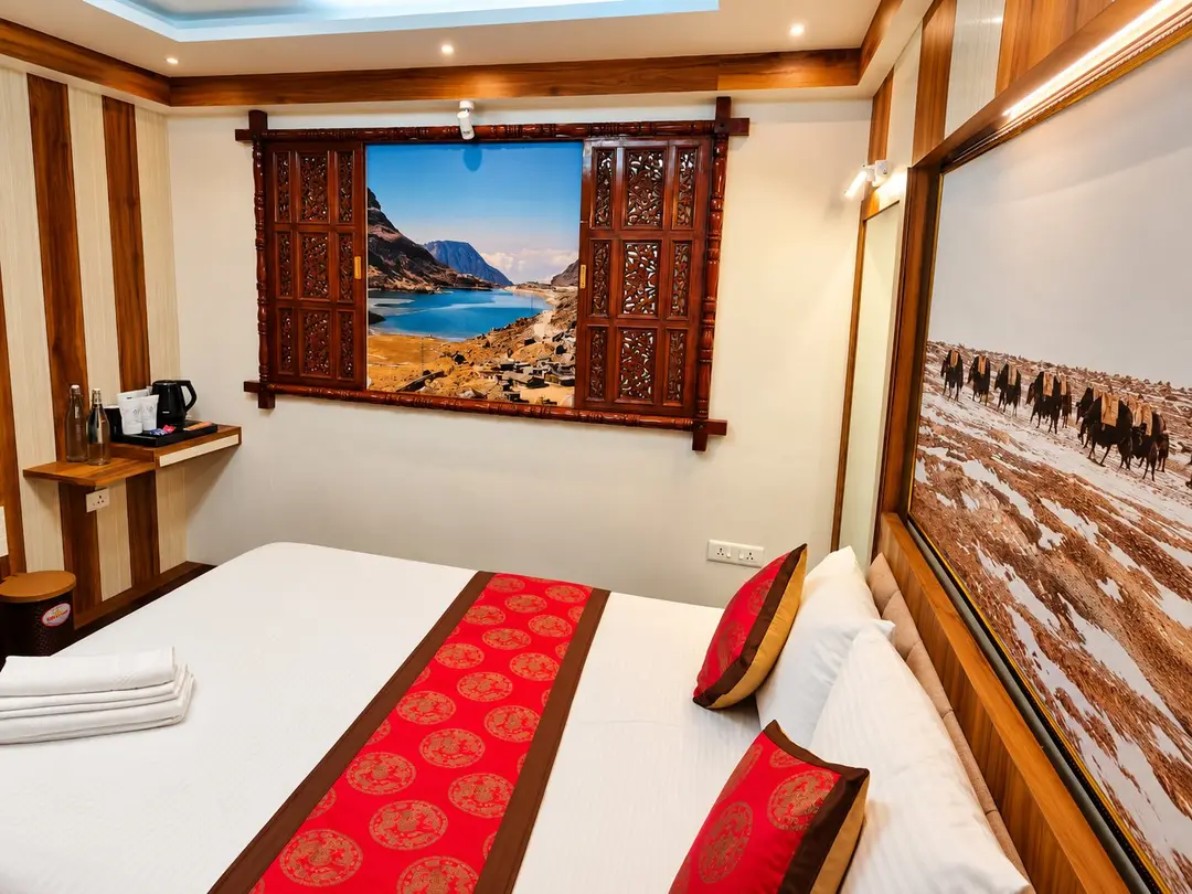 Hand-carved wooden window frame around a mountain-lake photograph beside the bed in the Executive Room