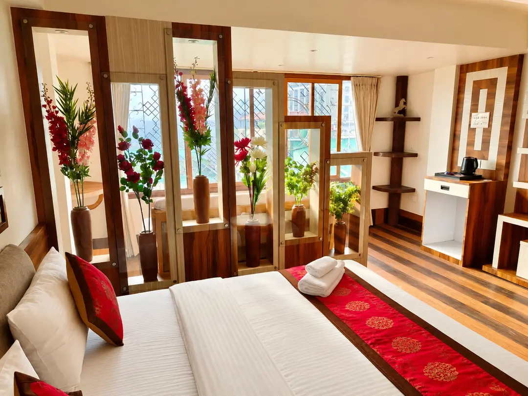Suite bedroom with a king-size bed, red silk runner and a timber screen of floral niches in front of the windows